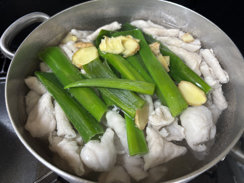 茹でた豚ホルモン、ネギの青い部分、ショウガ、日本酒を入れて10分煮る